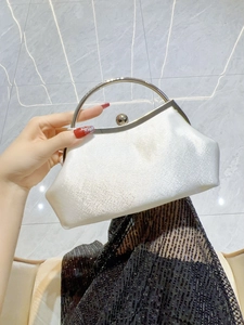 Detail of white satin evening bag with metal ring handle and glossy sphere clasp