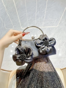 Detail of black evening bag featuring 3D floral accents and silver round metal handle