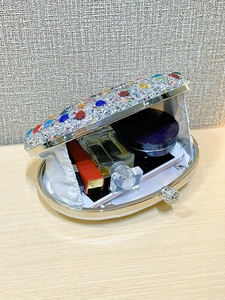 Macro view of crystal evening bag interior holding lipstick, perfume and phone