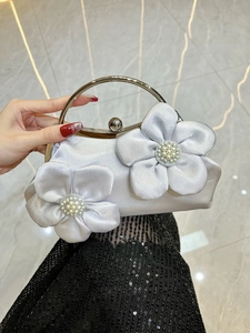 Detail of silver satin evening clutch featuring large handmade fabric flowers and pearls