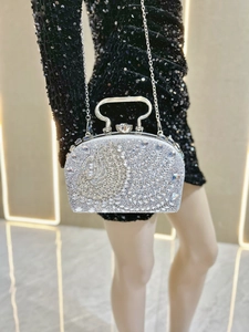 Primer plano de bolso de fiesta plateado con diamantes, asa de anillo y cadena fina