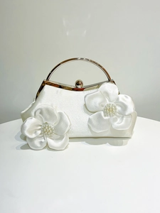 Detail of cream satin evening clutch with 3D floral accents and pearl beaded center