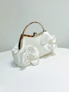 Detail of white satin evening bag featuring handmade fabric flowers and pearl accents
