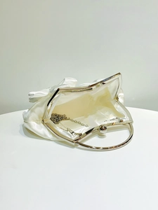Detail of ivory satin evening clutch bag interior with silver chain strap and metal handle