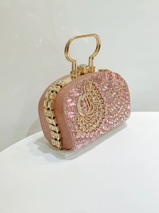Detalle macro de bolso de fiesta rosa con pavé de diamantes y diseño de pavo real dorado