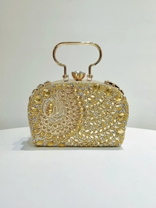 Detalle del bolso de noche dorado con diseño de pavo real en strass y asa de metal
