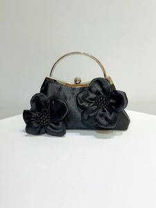 Detail of black satin evening clutch with 3D handmade flowers and silver metal ring handle