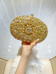 Detail of gold evening clutch with radiating crystal flower pattern held by a model
