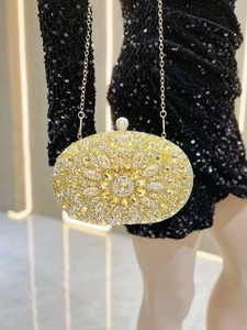 Close-up of golden floral rhinestone clutch bag paired with a black sequin evening dress
