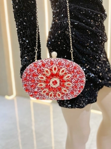 Detail of red oval clutch bag with rhinestone floral pattern and golden chain strap