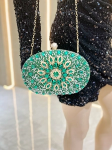 Macro view of emerald green crystal floral pattern and gold chain on the evening clutch