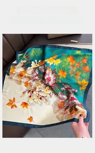 Close-up of floral satin scarf featuring magnolia and maple leaf patterns with hemmed edges