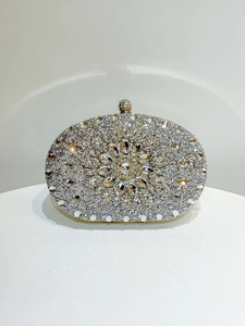 Detail of silver evening clutch bag featuring floral rhinestone patterns and a spherical clasp