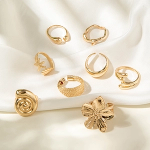 8-piece gold starfish and shell open ring set on white silk fabric background