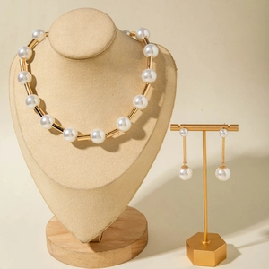 Detail of faux pearl necklace and linear earrings set on a velvet display stand