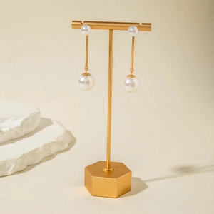 Detail of elegant gold drop earrings with large white pearls on a display stand