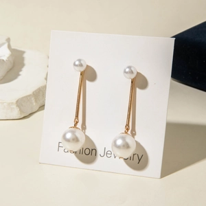 Elegant gold drop earrings with white imitation pearls on a Fashion Jewelry display card