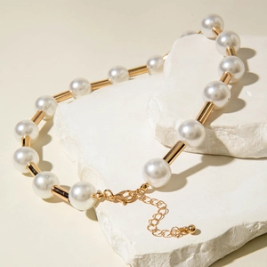 Minimalist pearl necklace with gold tube accents on marble stone for a luxury look