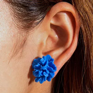 Detailed view of model wearing a 3D blue floral stud earring with layered petals