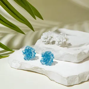 Detail of elegant 3D flower studs in pearly white and shimmering blue on white stones