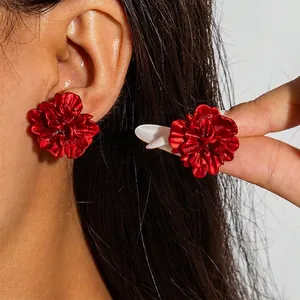Macro detail of deep red 3D flower earrings with textured petals and secure white backings