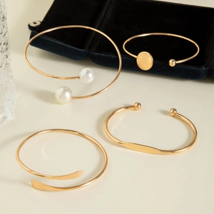 Close-up of golden stackable bracelets with pearls and round discs on a velvet box