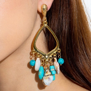 Detalle de pendientes bohemios dorados con cuentas de turquesa y conchas de mar reales
