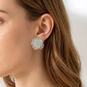 Close-up of blue floral resin earrings with glitter details and wavy petal texture