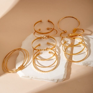 Stackable gold bangle set with open cuffs and pearl accents on elegant stone props