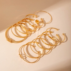 Macro view of 14-piece gold plated bracelet set featuring minimalist textures and knot details