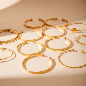 Detailed close-up of various textured gold-plated open bangles with polished and hammered finishes