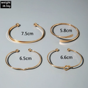 Detail view of four gold layered bangles with pearl and knot accents showing dimensions