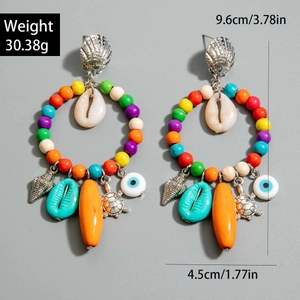 Vista detallada de pendientes de coral boho con conchas y dijes de tortuga marina