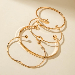 Detailed view of a four-piece gold-plated knot and bead adjustable stacking bracelet set