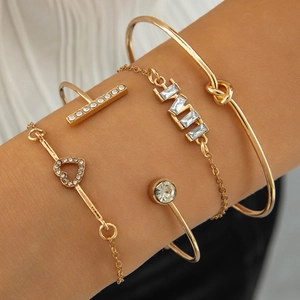 Detail of four-piece gold layered bracelet set with heart charms and crystal accents