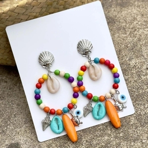 Detalle de aros bohemios con cuentas de colores, conchas y colgantes marinos