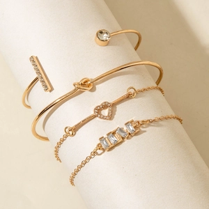 Detail of four-piece gold bracelet set with LOVE charm and crystal heart on display