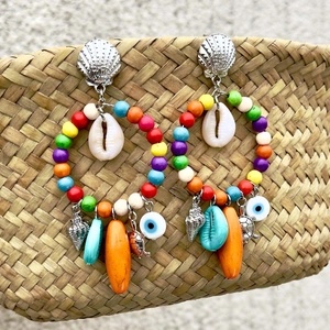 Detalle de pendientes de aro bohemios con conchas y colgantes de tortuga turquesa
