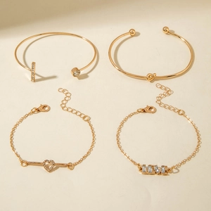Close-up of four-piece gold jewelry set including open bangles and LOVE heart bracelets