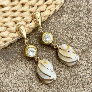 Detalle de pendientes de coral con colgantes de concha y detalles de metal dorado
