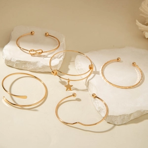 Detail of 5-piece gold bangle set with star charms and diverse textured metal finishes