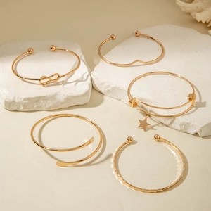 Close-up of five-piece gold bracelet set with star charms and hammered textures