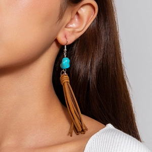 Detalle de pendientes estilo coral bohemio con piedra azul y flecos largos de ante marrón