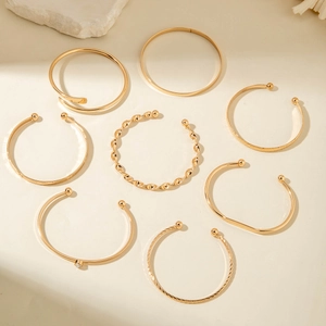 Detailed set of 8 gold bracelets featuring pearls and diverse geometric textures