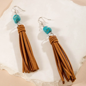 Detalle de pendientes rama de coral bohemio con cuentas turquesas y borlas de ante marrón
