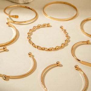Close-up of elegant gold bangles featuring pearl accents and intricate spiral designs
