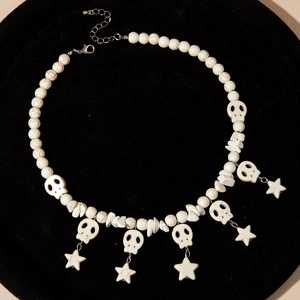 Gothic beaded necklace with white skull charms and star pendants on black velvet tray