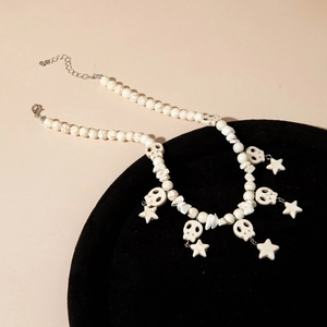 Bohemian white turquoise beaded necklace with skull and star charms on black display