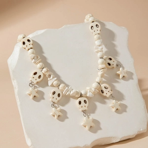 Gothic punk skull necklace with white turquoise beads and star pendant on stone background