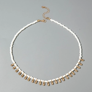 Détail du collier bohème avec perles blanches et pendentifs dorés en forme de goutte